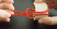 two hands are working on a piece of paper with red string attached to the end