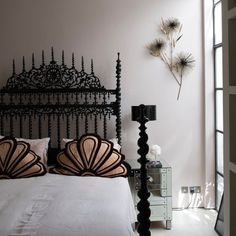 a bedroom with white walls and black iron bed frame, decorative flowers on the wall