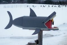 a mailbox with a shark painted on it's side in the middle of snow