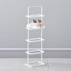 a white shoe rack with three pairs of shoes on top and one pair in the bottom