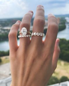 a woman's hand with two wedding rings on top of her finger, overlooking the water