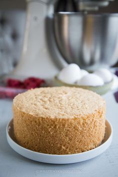 a cake sitting on top of a white plate next to a mixing bowl and mixer