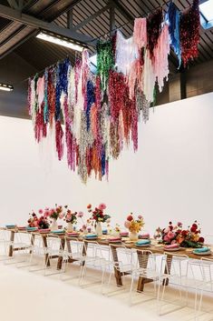 a long table with plates and flowers on it in front of a hanging chandelier