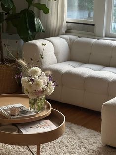 a living room filled with furniture and flowers on top of a coffee table in front of a window