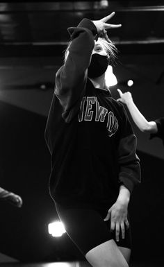 a woman with her hands up in the air while wearing a sweatshirt and black shorts