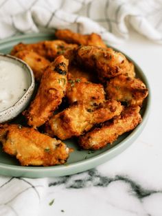 some fried food is on a plate with a small bowl of ranch dressing next to it