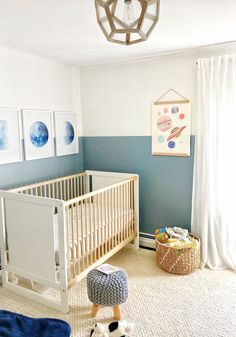 a baby's room with blue and white walls, a crib, rugs and pictures on the wall