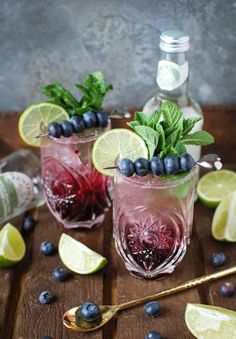 two glasses filled with blueberries and limes