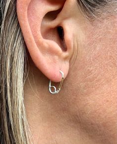 a close up of a person's ear wearing a pair of silver hoop earrings