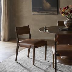 a dining room table with two chairs and a vase filled with flowers