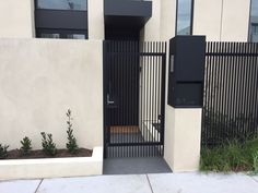 an entrance to a building with a black gate and planters on the side walk