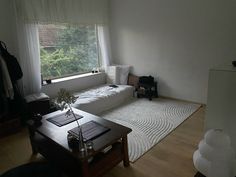 a living room with a couch, coffee table and large window in the corner that overlooks trees