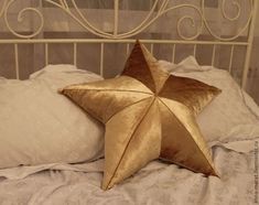 a gold star pillow sitting on top of a white bed