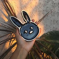 a hand holding up a black and white bunny sticker