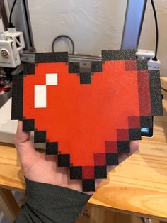 a person holding up a piece of art made to look like a heart