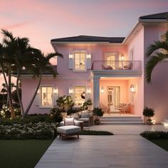 a large pink house with palm trees in the front yard at dusk, lit up by outdoor lighting