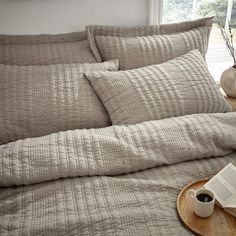 a coffee cup and book on a tray in front of a quilted comforter