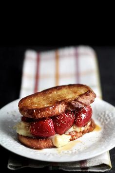 a white plate topped with a sandwich covered in cheese and strawberries