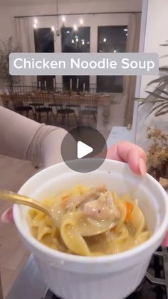 a person holding a bowl of chicken noodle soup