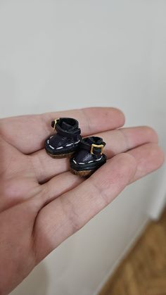 a person holding two tiny black shoes in their hand