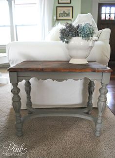 a white vase sitting on top of a wooden table next to a couch in a living room