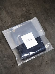 an empty plastic bag sitting on top of a cement floor next to a white square sticker