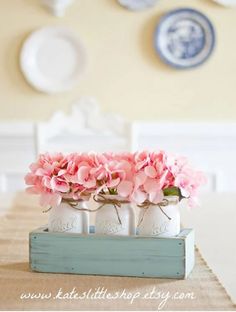 pink flowers are in mason jars on a table