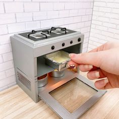 a person is opening the door to a small stove that has been placed on top of a wooden table