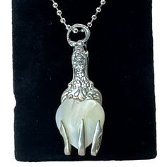 a silver necklace with a white cow on it's back and a chain hanging from the neck