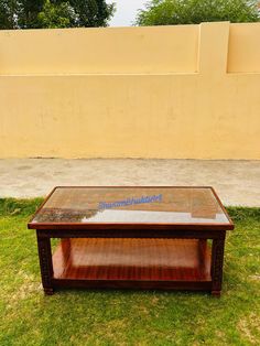 a coffee table sitting on top of a lush green grass covered field next to a yellow wall