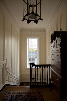 an empty room with a chandelier hanging from the ceiling and a rug on the floor