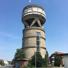 a tall tower with a clock on the side of it's face next to trees and buildings