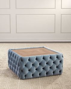 a blue ottoman sitting on top of a carpet next to a white wall and door