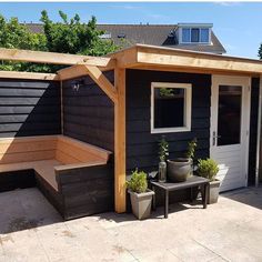 a small black shed with potted plants on the outside