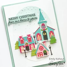 a close up of a christmas card with a small house on the front and trees in the back