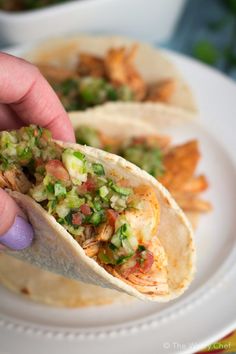 a person is holding a tortilla on a plate with shrimp and guacamole