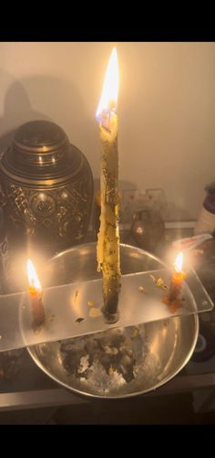 a lit candle sitting on top of a metal plate