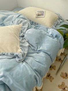 a bed with blue sheets and pillows on top of it next to a potted plant