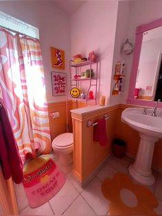 a bathroom with pink and orange decor on the shower curtain, toilet, sink and mirror