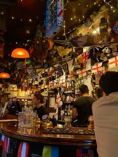 people sitting at a bar with flags hanging from the ceiling and decorations on the walls