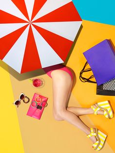 a woman laying on the ground with an umbrella over her head and other items around her