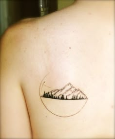 a small mountain tattoo on the back of a woman's shoulder