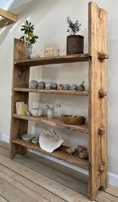 an old wooden shelf with pots and plants on it in the corner of a room