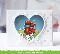 a heart shaped card with a teddy bear hugging it's back in the grass