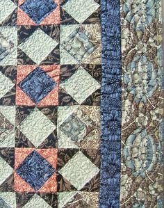 a close up of a quilt on a table cloth with blue and orange squares in the center