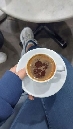 a person holding a cup of coffee in their hand