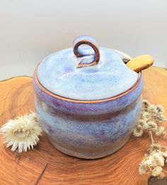 a blue pot sitting on top of a wooden table next to dried flowers and a piece of wood