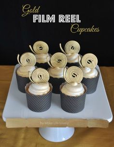 cupcakes with white frosting and gold swirl decorations on a cake platter