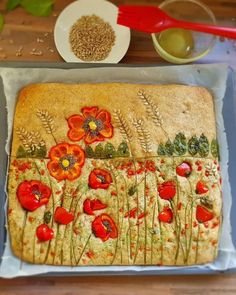 a cake decorated with red flowers and green leaves on top of a table next to a bowl of oatmeal