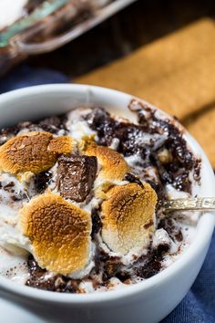 a bowl filled with pudding and marshmallows on top of a blue cloth